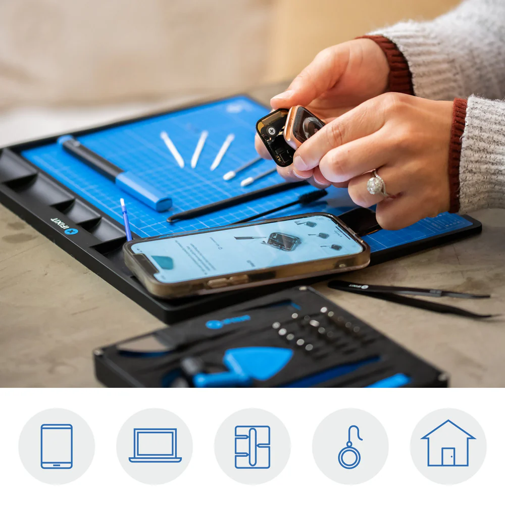 Hände halten Smartwatch, über Telefon und Werkzeugset auf blauer Matte. Hände der Frau, Ring sichtbar.