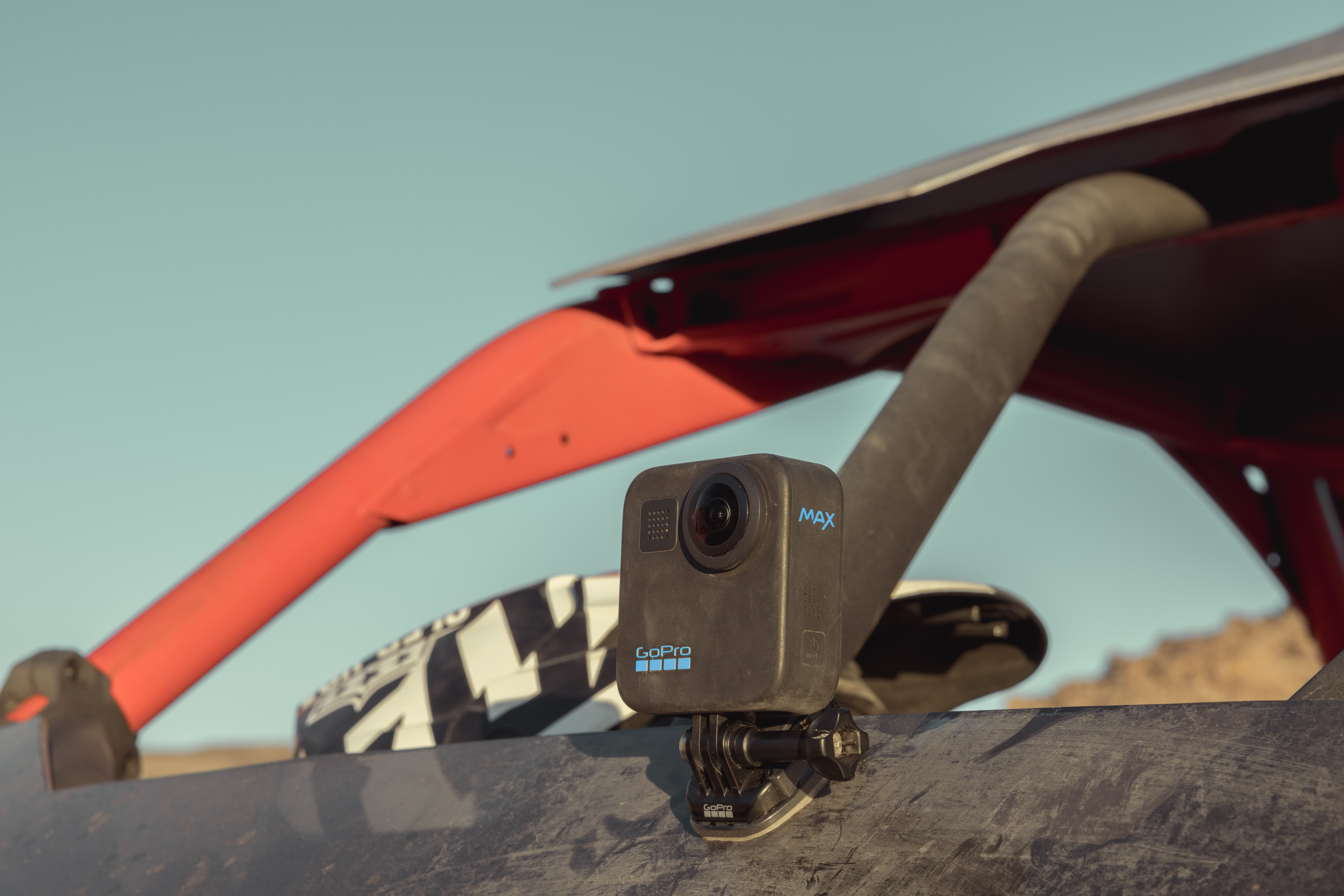 GoPro Max-Kamera an einem Fahrzeug montiert, mit rotem Überrollkäfig. Der Hintergrund ist ein klarer blauer Himmel.