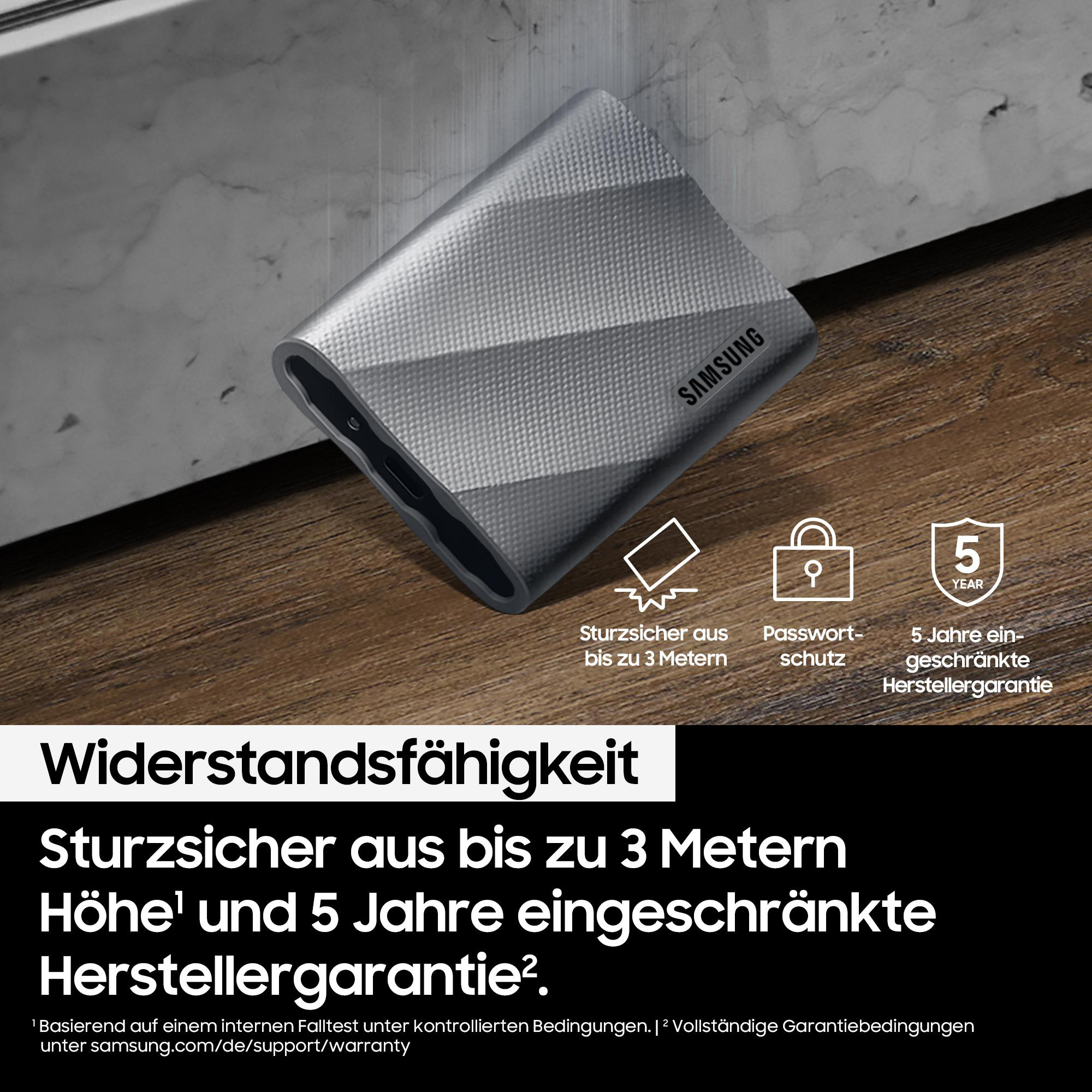 Silberne Samsung externe Festplatte. Merkmale: Sturzfestigkeit und 5 Jahre Garantie. Der Hintergrund ist eine Holzoberfläche.