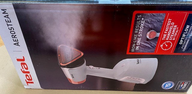 Żelazko parowe Tefal w pudełku, z wydobywającą się parą. Pudełko pokazuje szczegóły produktu.