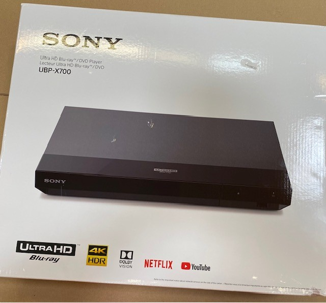 Czarny odtwarzacz Blu-ray w pudełku, z logo. Białe tło.