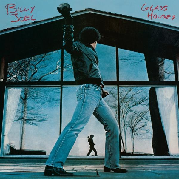 Albumcover mit Billy Joel, der einen Stein auf ein Haus wirft. Glass Houses Album.