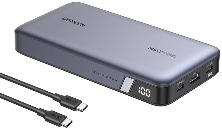Szürke power bank, 100-at mutat a kijelzőn, USB-C portokkal és UGREEN kábelekkel.