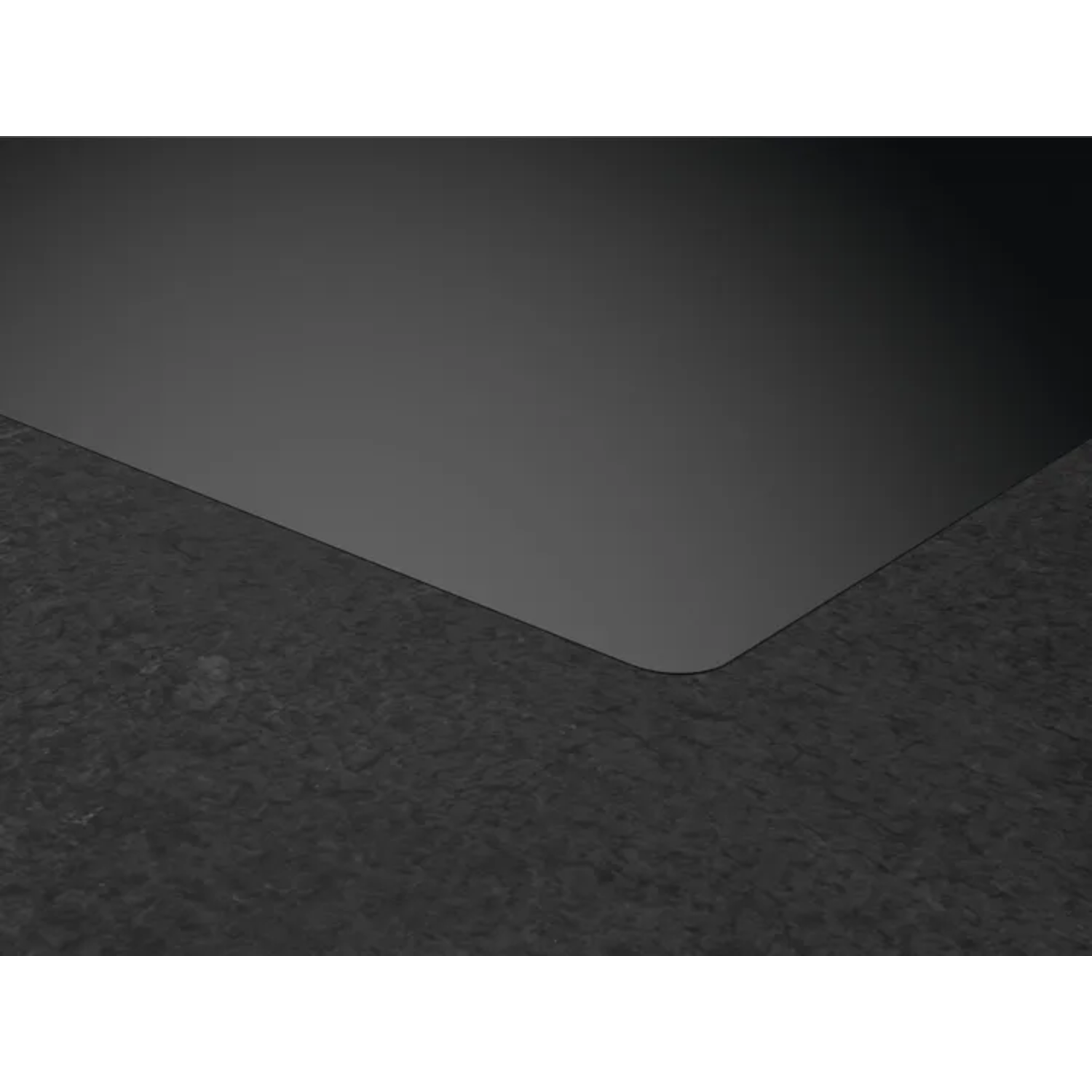 Black induction cooktop corner. Dark gray countertop in the foreground.