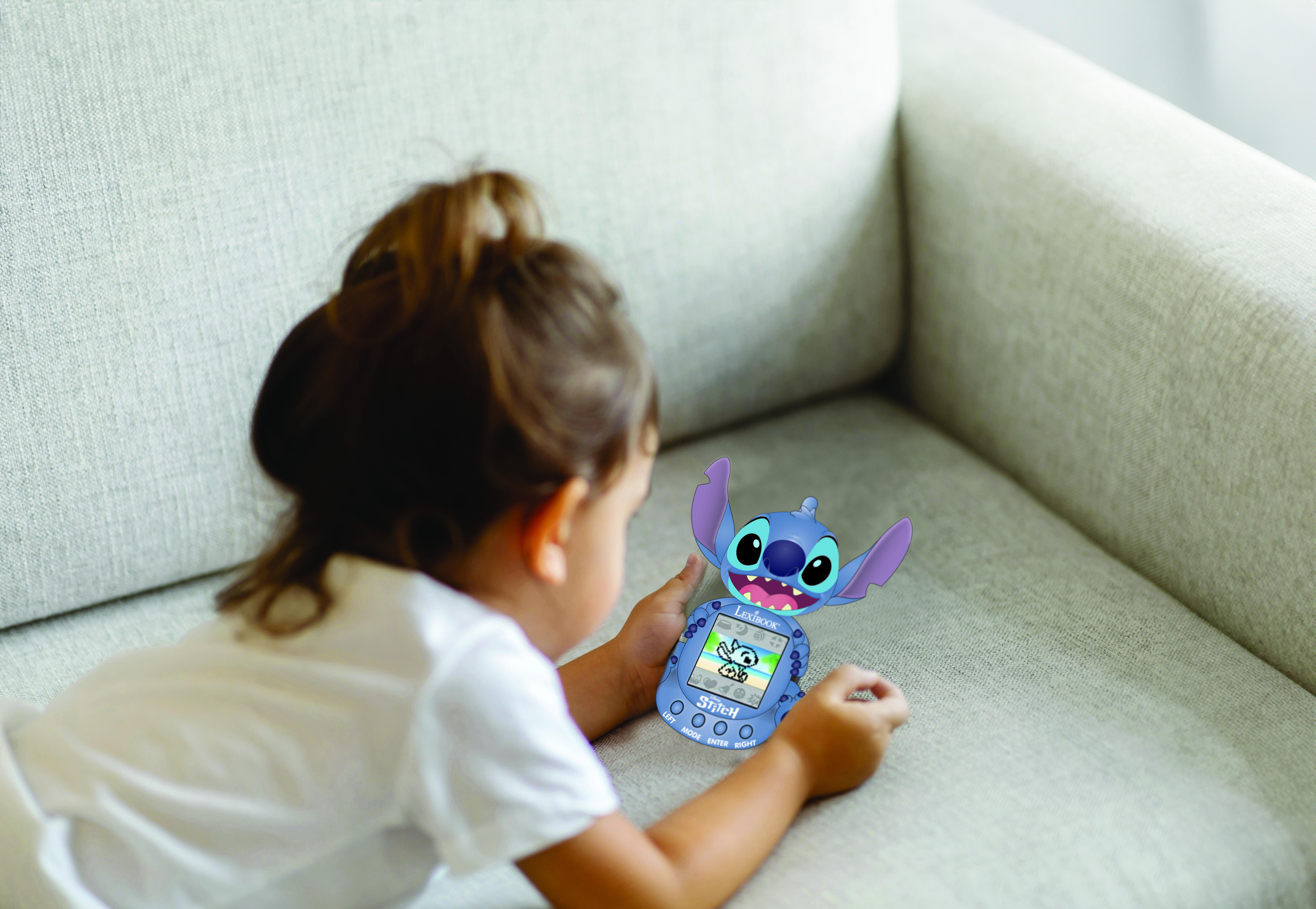 Ein Mädchen hält ein Stitch-Spielzeug und schaut es auf einem grauen Sofa an.