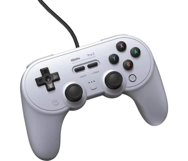 Srebrny kontroler 8BitDo Pro 2, widok pod kątem. D-pad, przyciski, gałki analogowe i kabel.