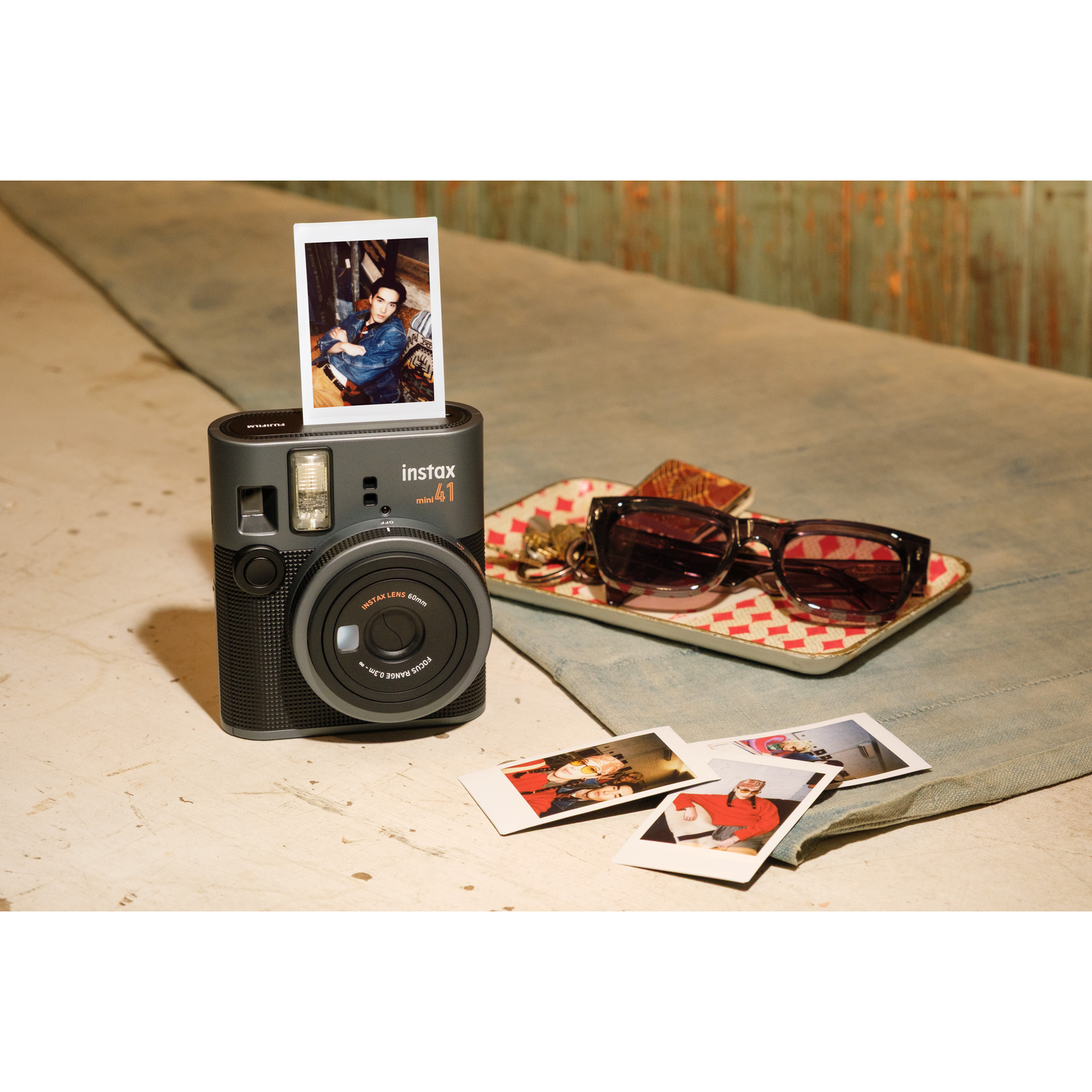 Instax mini 41 camera with sunglasses and photos.