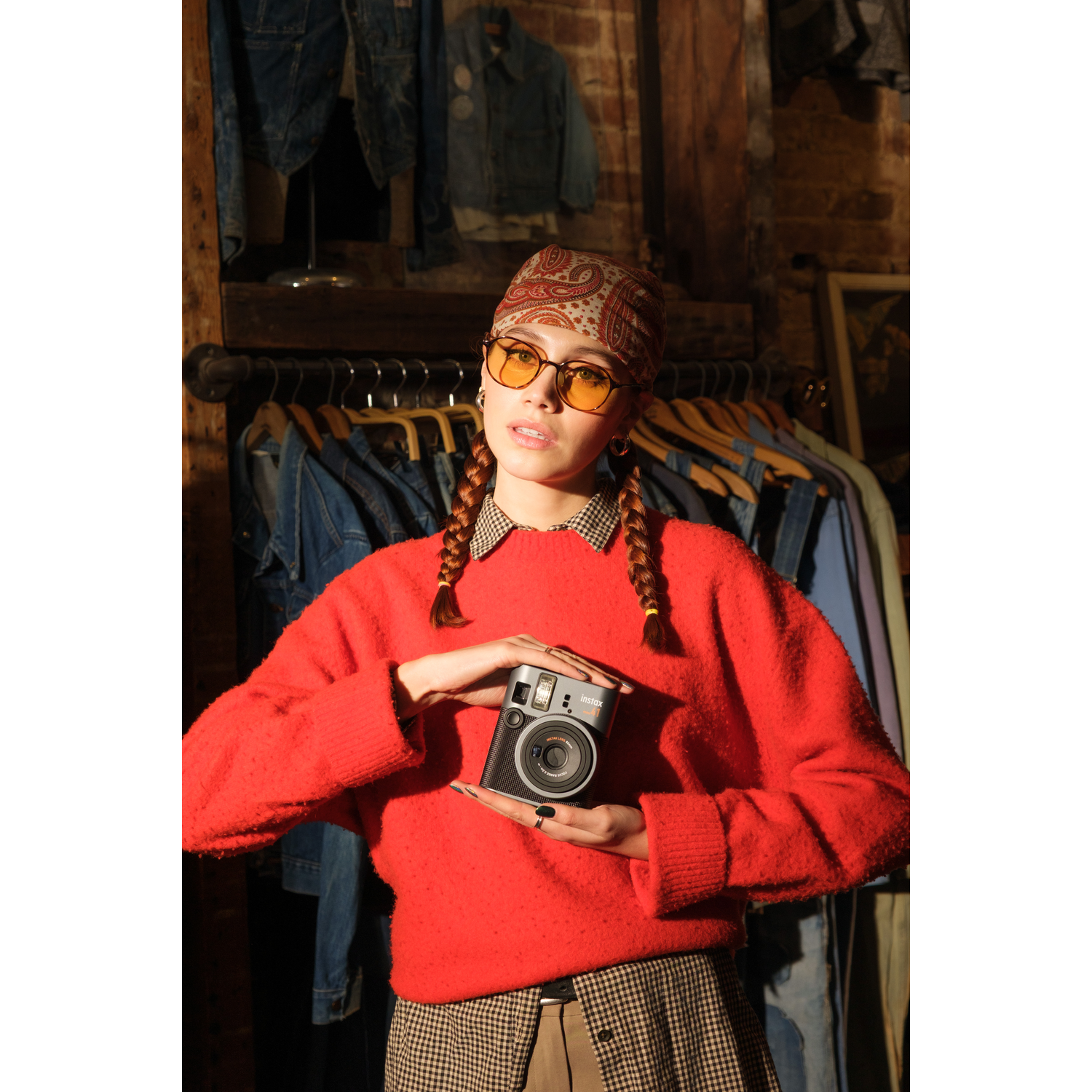 A person in red sweater holds an Instax Mini 41 camera. Background is a clothing store.