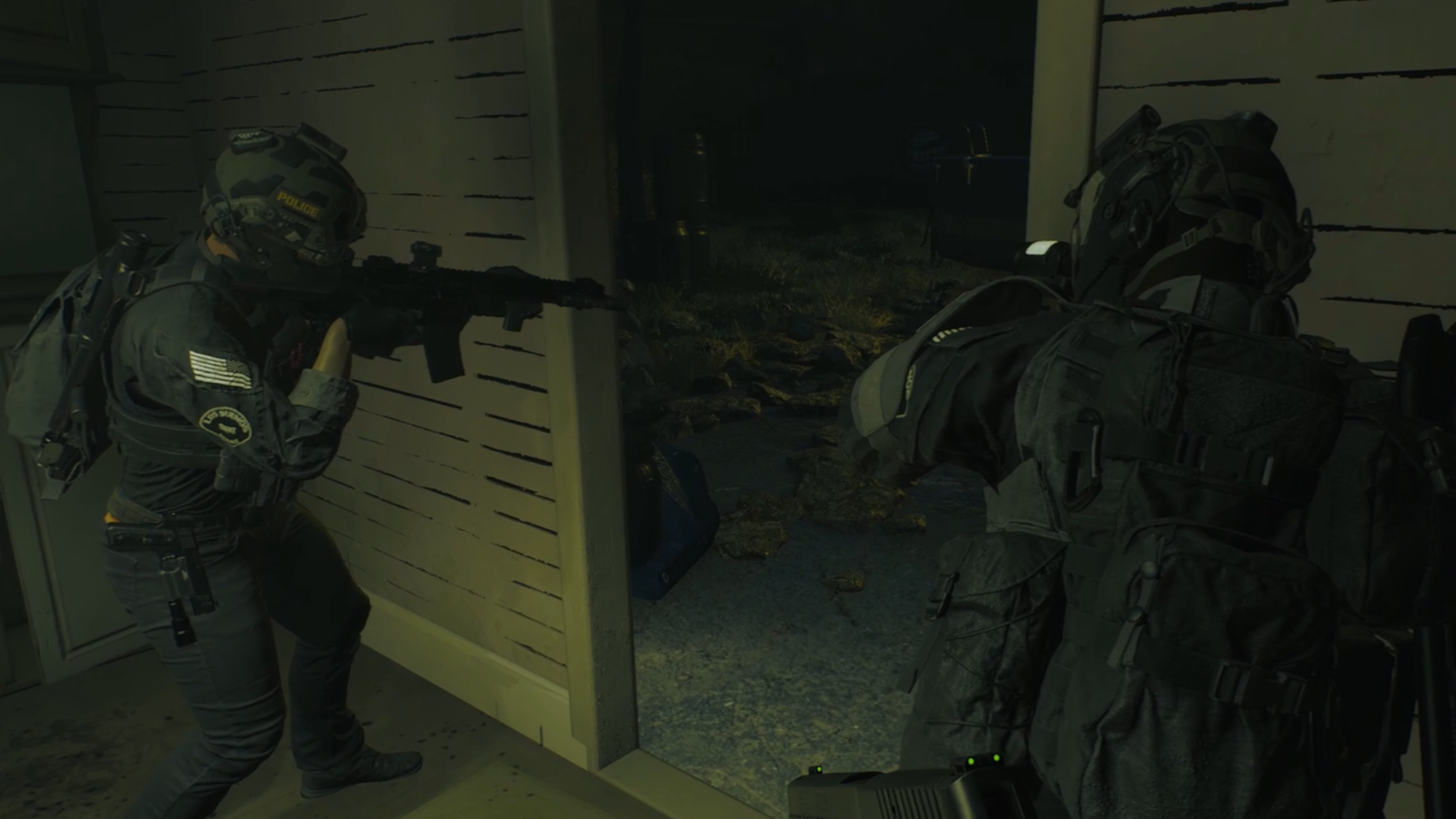 Escena de entrada interior: oficiales armados entrando en una habitación oscura. Uno apunta con arma.