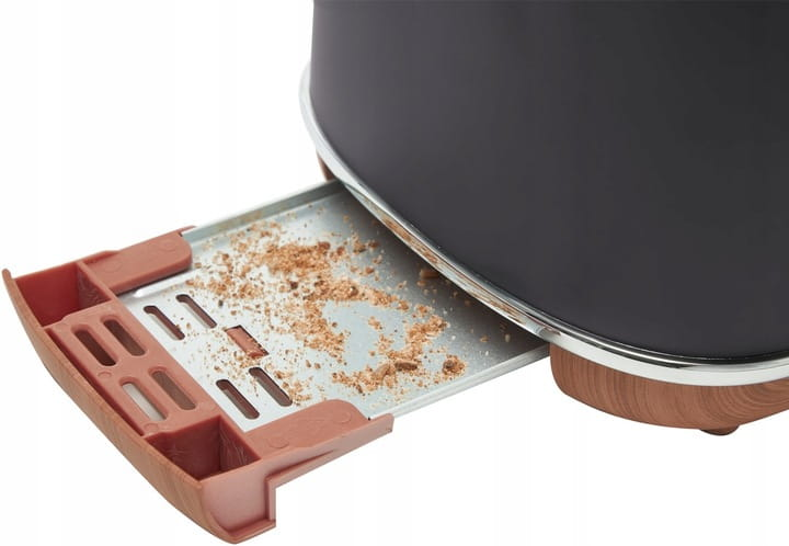 Zbliżenie na tackę na okruchy szarego tostera z okruchami w środku. Widoczne elementy drewniane i metalowe.