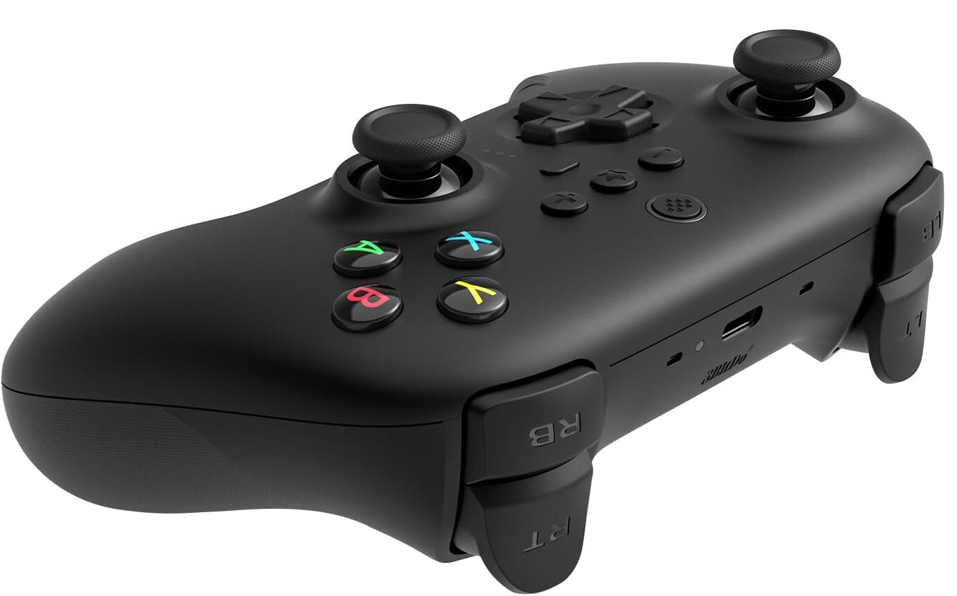 Czarny gamepad z kolorowymi przyciskami. Ma joysticki i przyciski na ramionach. Przyciski są kolorowe.