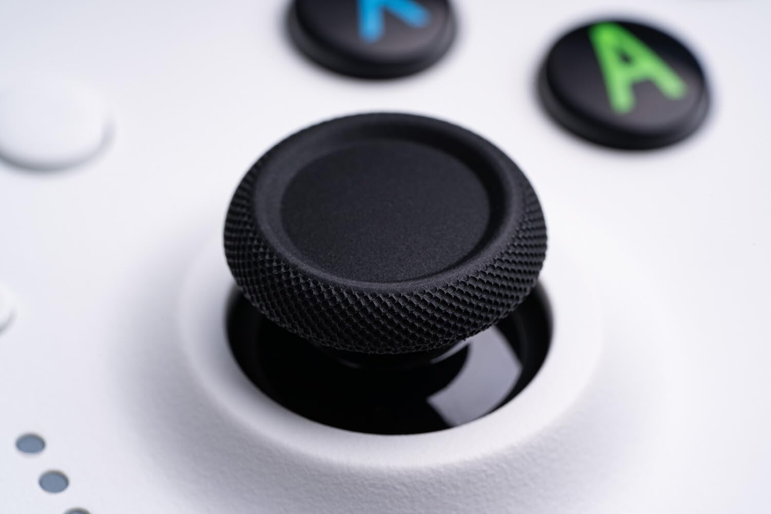 Zbliżenie czarnego joysticka na białym kontrolerze Xbox. Joystick ma teksturowaną powierzchnię.