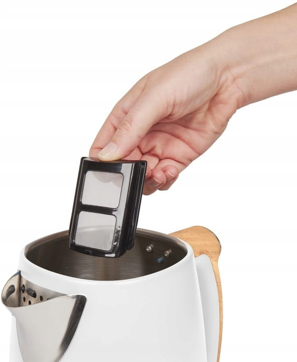 Ręka trzyma czarny filtr nad białym i ze stali nierdzewnej czajnikiem. Czajnik ma drewniany uchwyt.