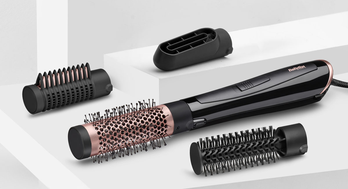 Narzędzie do stylizacji włosów z różnymi załącznikami na białym tle.