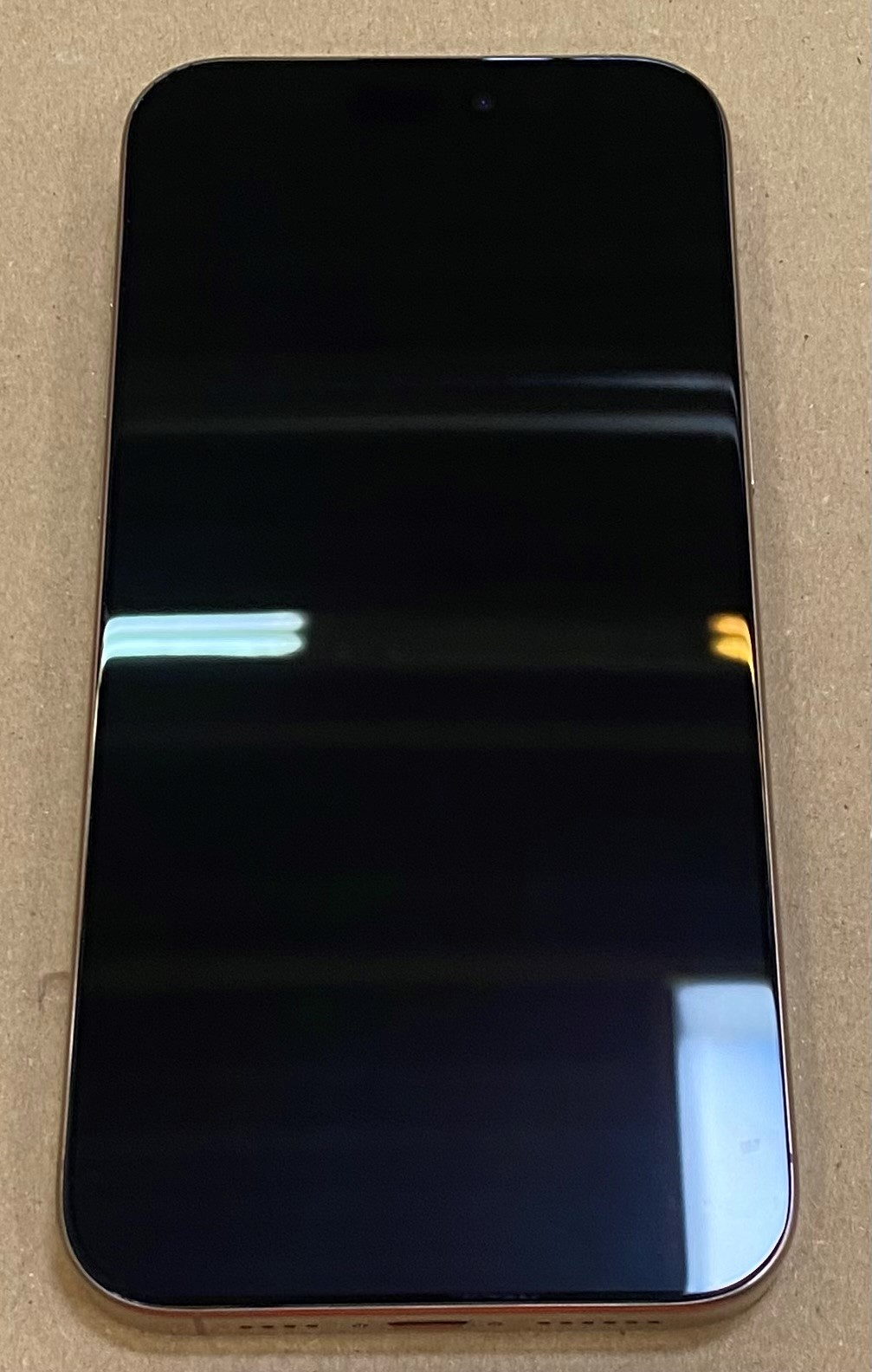 Przód iPhone'a. Czarny ekran, złota ramka. Ekran wyświetla ciemny obraz.