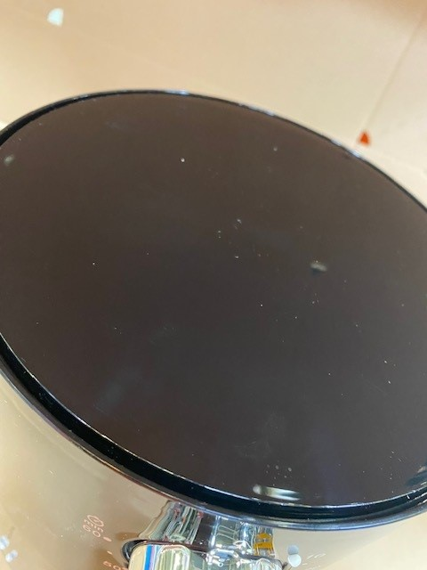 Czarna błyszcząca powierzchnia z maleńkimi białymi kropkami. Powierzchnia jest na ciemnym garnku.