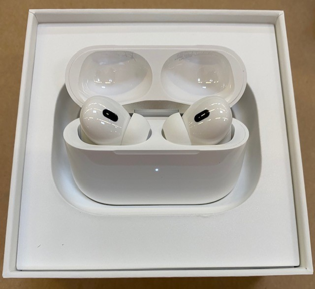 Białe Apple AirPods Pro w etui ładującym, otwarte. Wewnątrz białego pudełka.