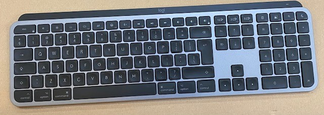 Klawiatura Logitech, szare i czarne klawisze, srebrna rama, w standardowym układzie.