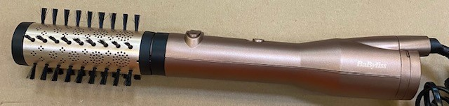 Rose gold styler do włosów z obrotową szczotką i czarnym włosiem. Marka to Babyliss.