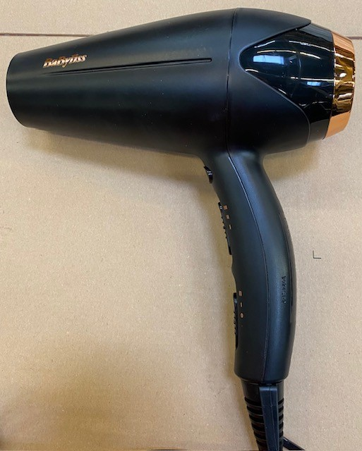 Czarna suszarka do włosów Babyliss. Ma czarny uchwyt i różowo-złotą dyszę.