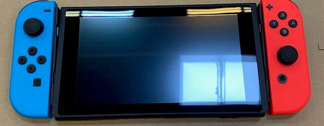 Konsola Nintendo Switch z niebieskimi i czerwonymi Joy-Conami. Ekran jest czarny.