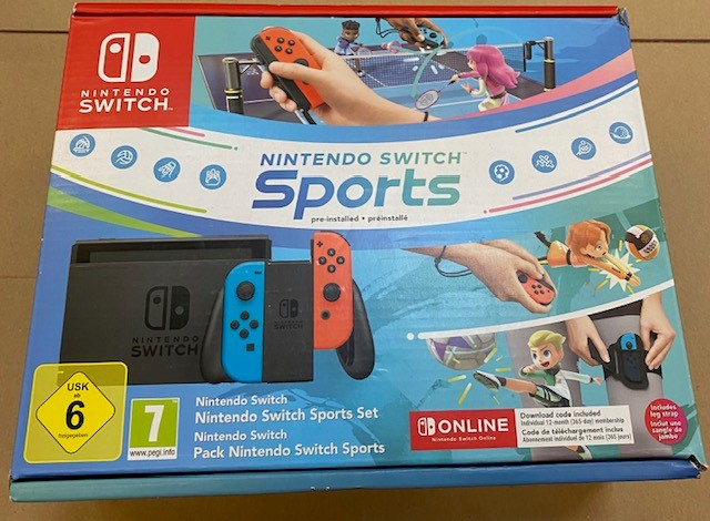 Pudełko z grą Nintendo Switch Sports. Pokazuje ludzi uprawiających sport. Konsola i kontrolery są widoczne.