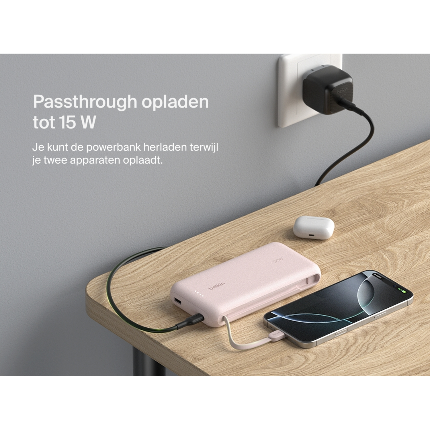 Belkin power bank charging a phone. Wall outlet in background. Table surface.