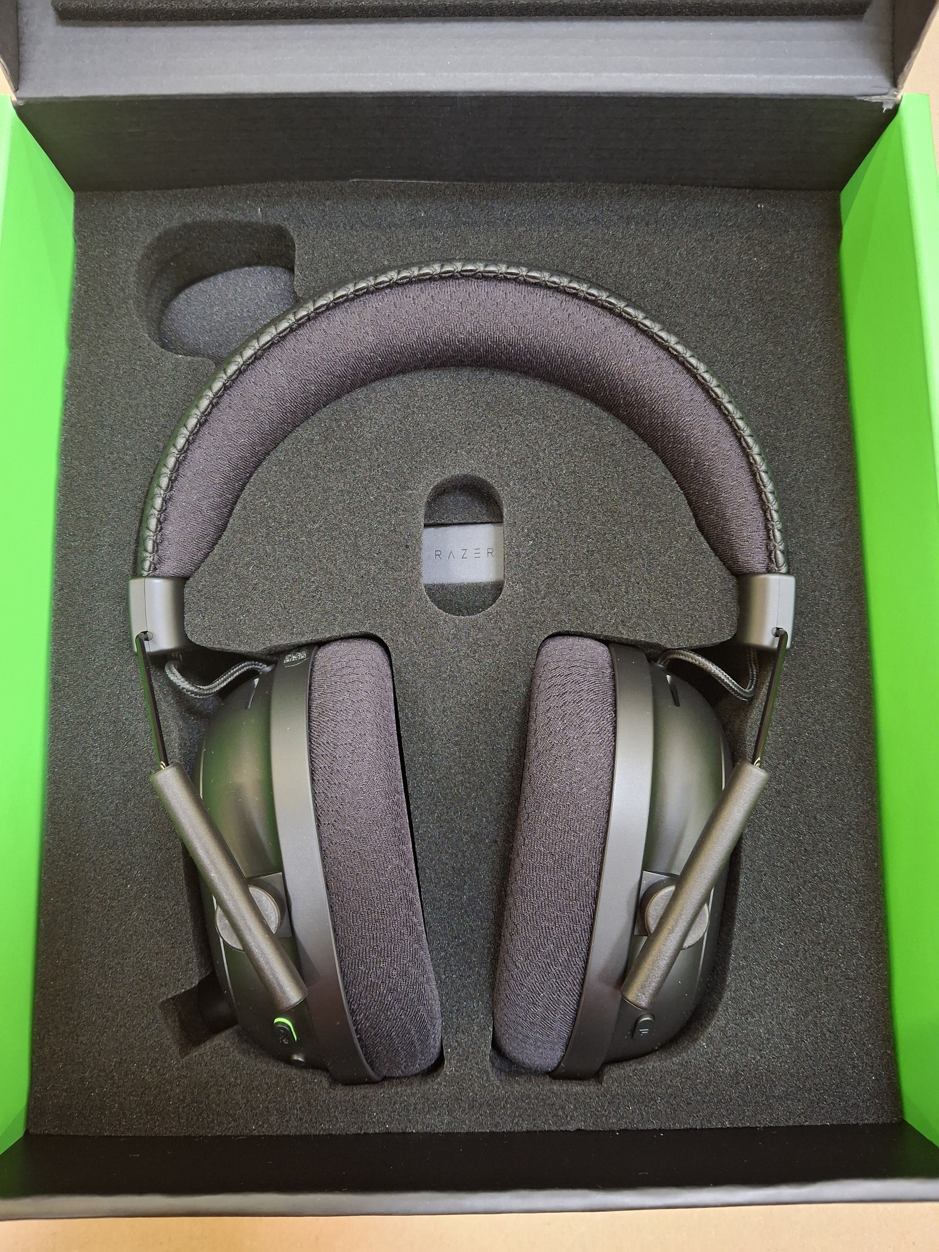 Czarne słuchawki Razer Blackshark V2 Pro. Czarne nauszniki. Zielone akcenty. Ciemne tło.