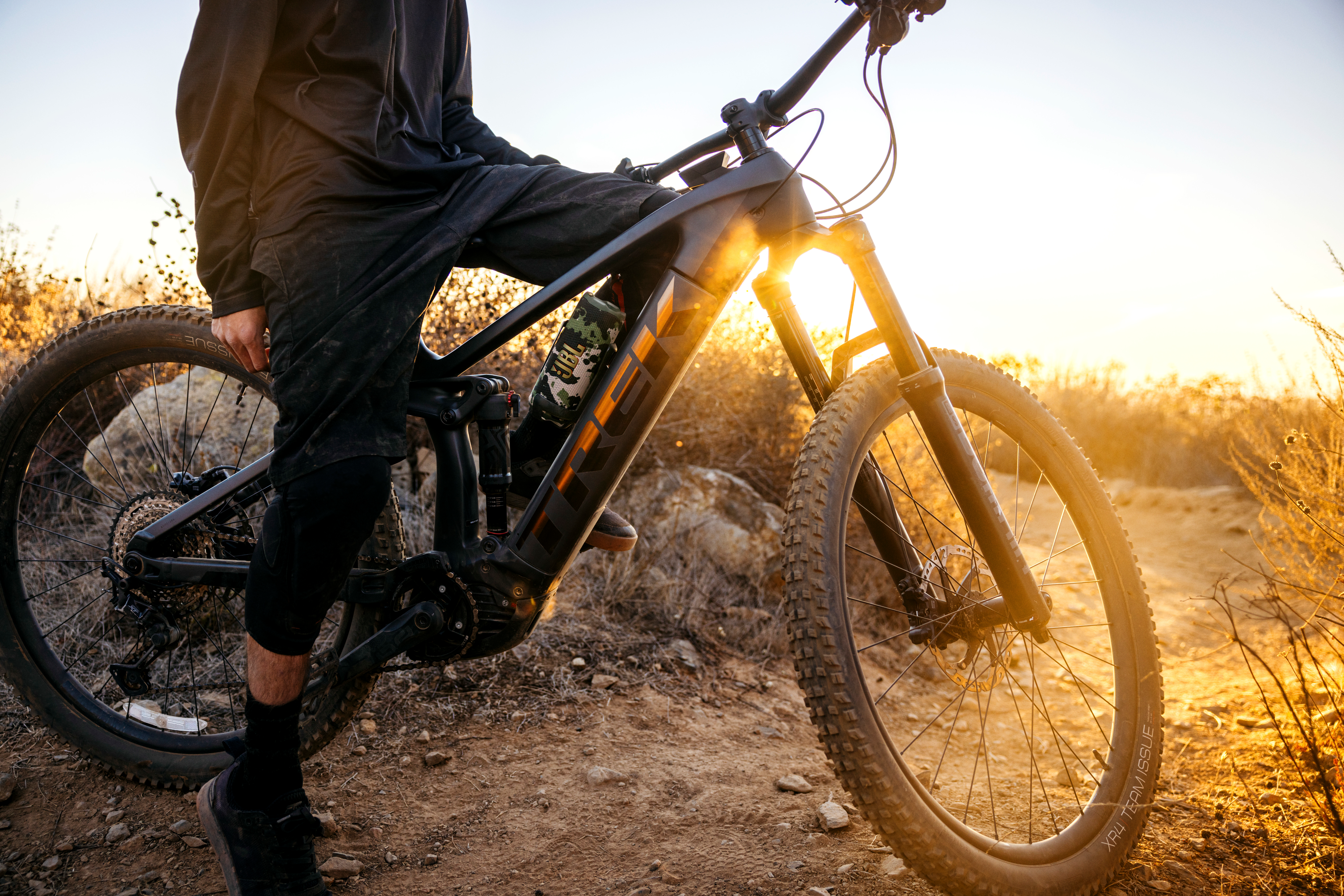 Person auf dem Fahrrad, Sonnenuntergang. Camouflage-Lautsprecher am Rahmen, orangenes Licht.