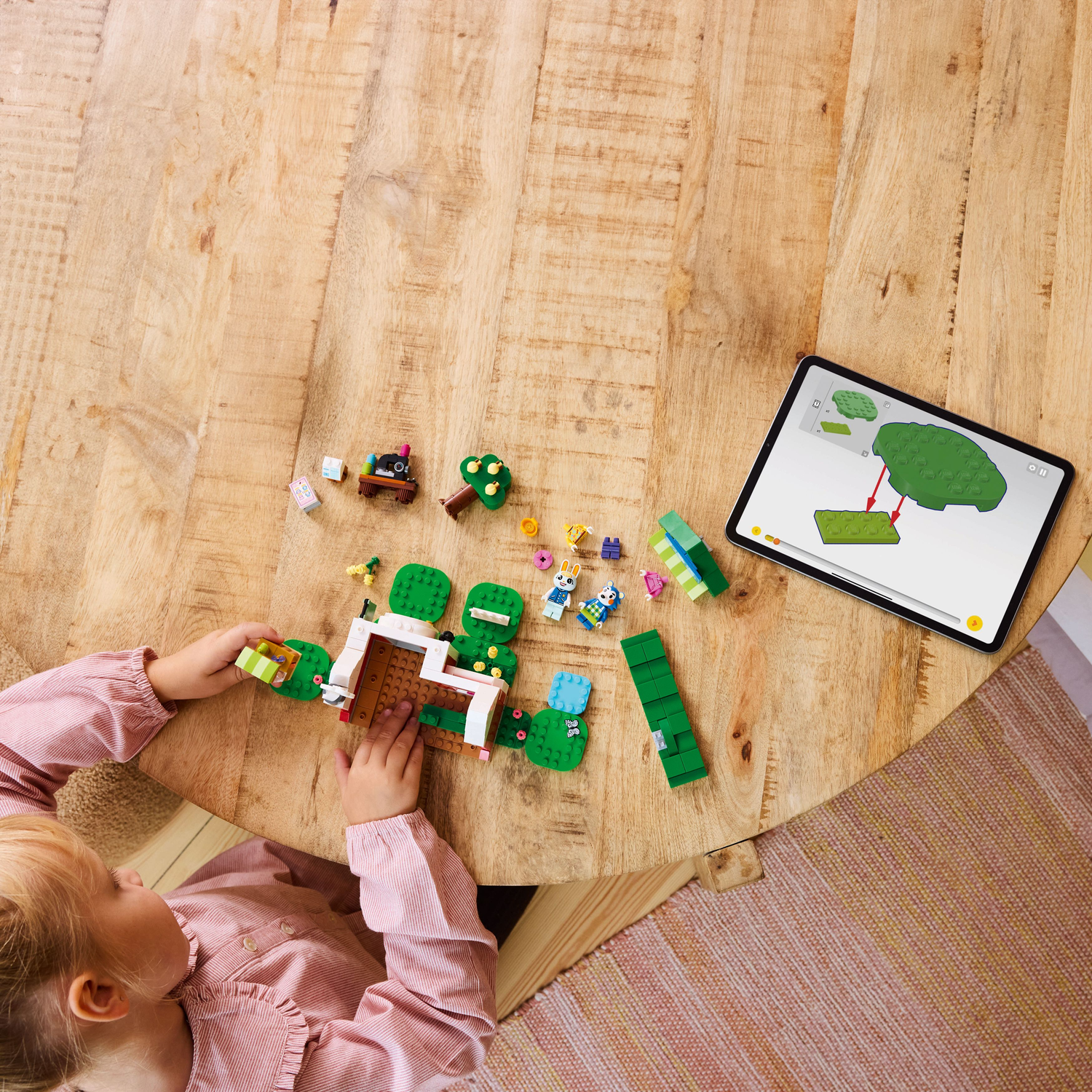 Child assembling LEGO Animal Crossing set on a wooden table. Tablet with instructions is visible.