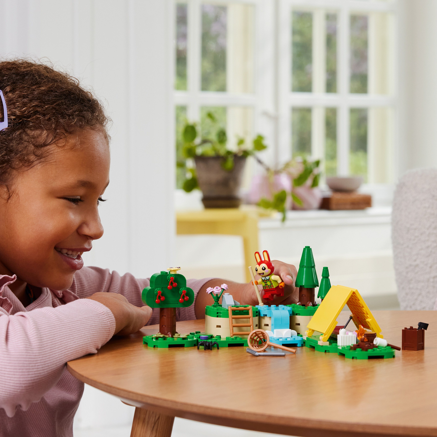 Girl playing with a LEGO Animal Crossing set featuring a camping scene with a bunny.
