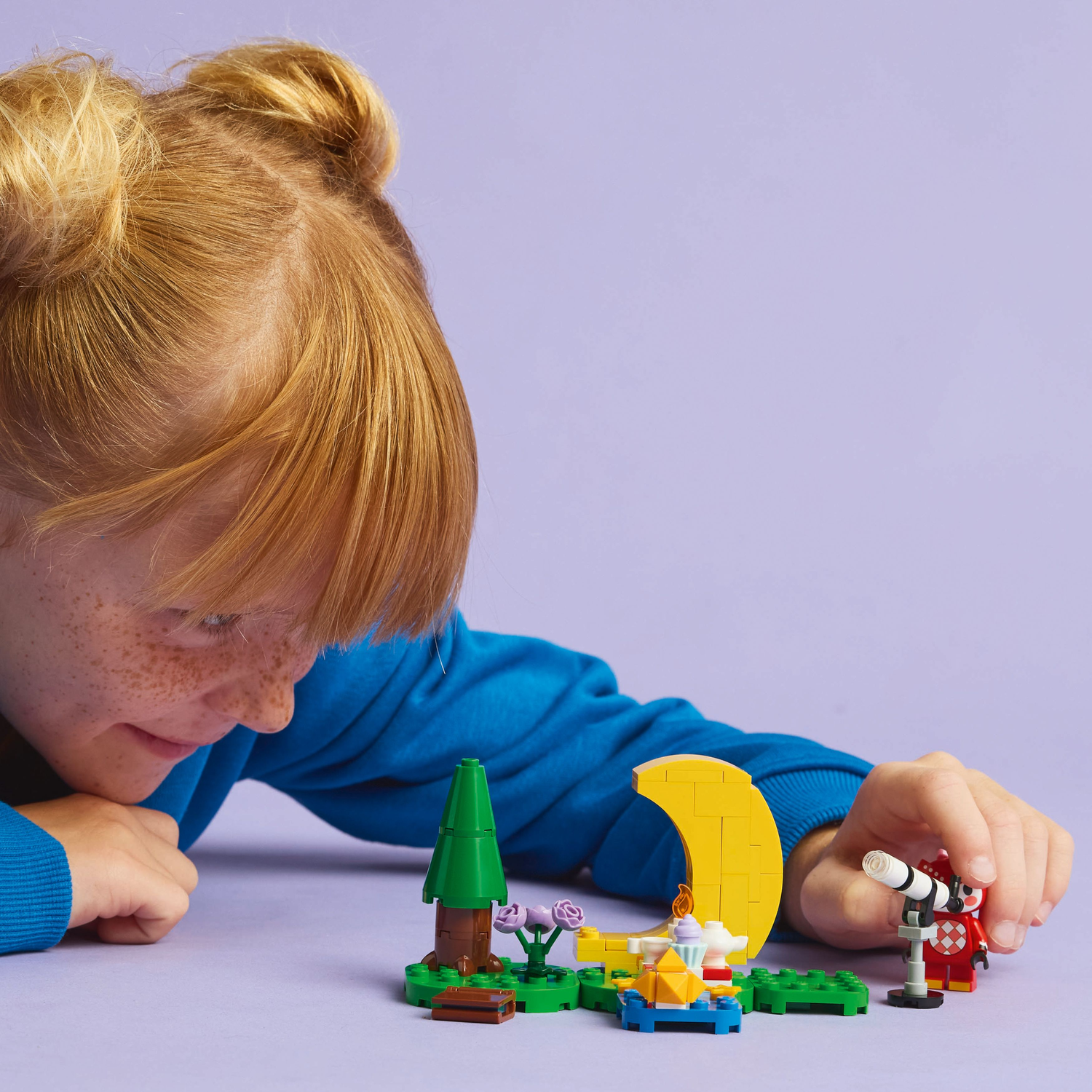 Girl playing with a LEGO Animal Crossing set, featuring a stargazing scene with a telescope.