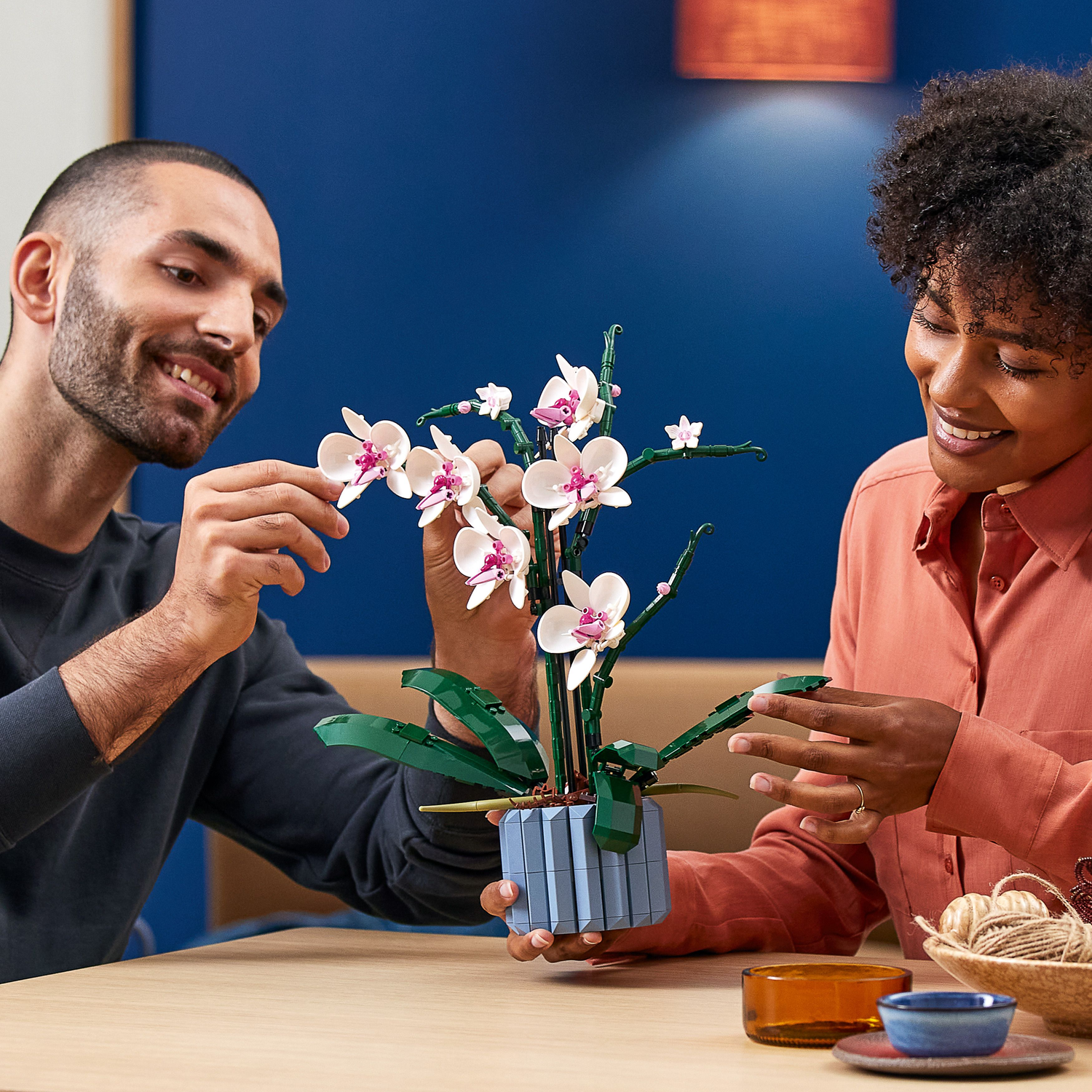 People with Lego orchid. Two people looking at a lego orchid on a table.
