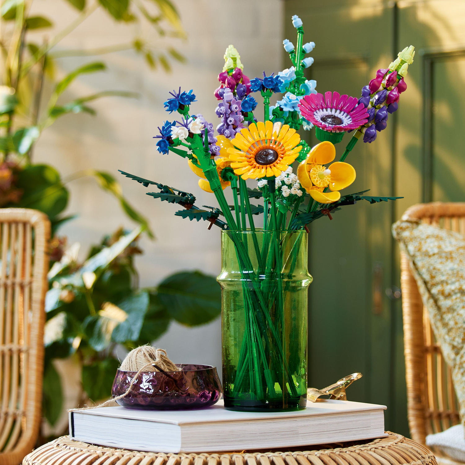 LEGO Wildflower Bouquet in een groene vaas op een tafel. Een boek en een kom ernaast. Interieur setting.