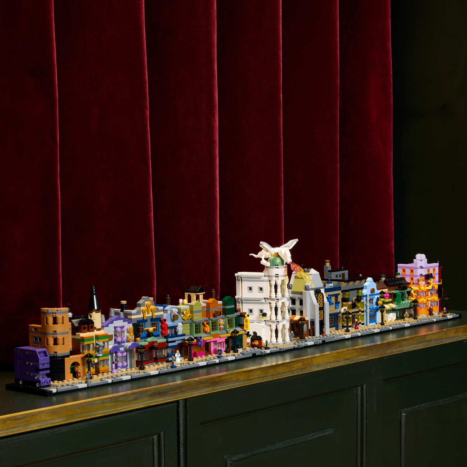 LEGO Diagon Alley set displayed on a shelf in front of a burgundy curtain.