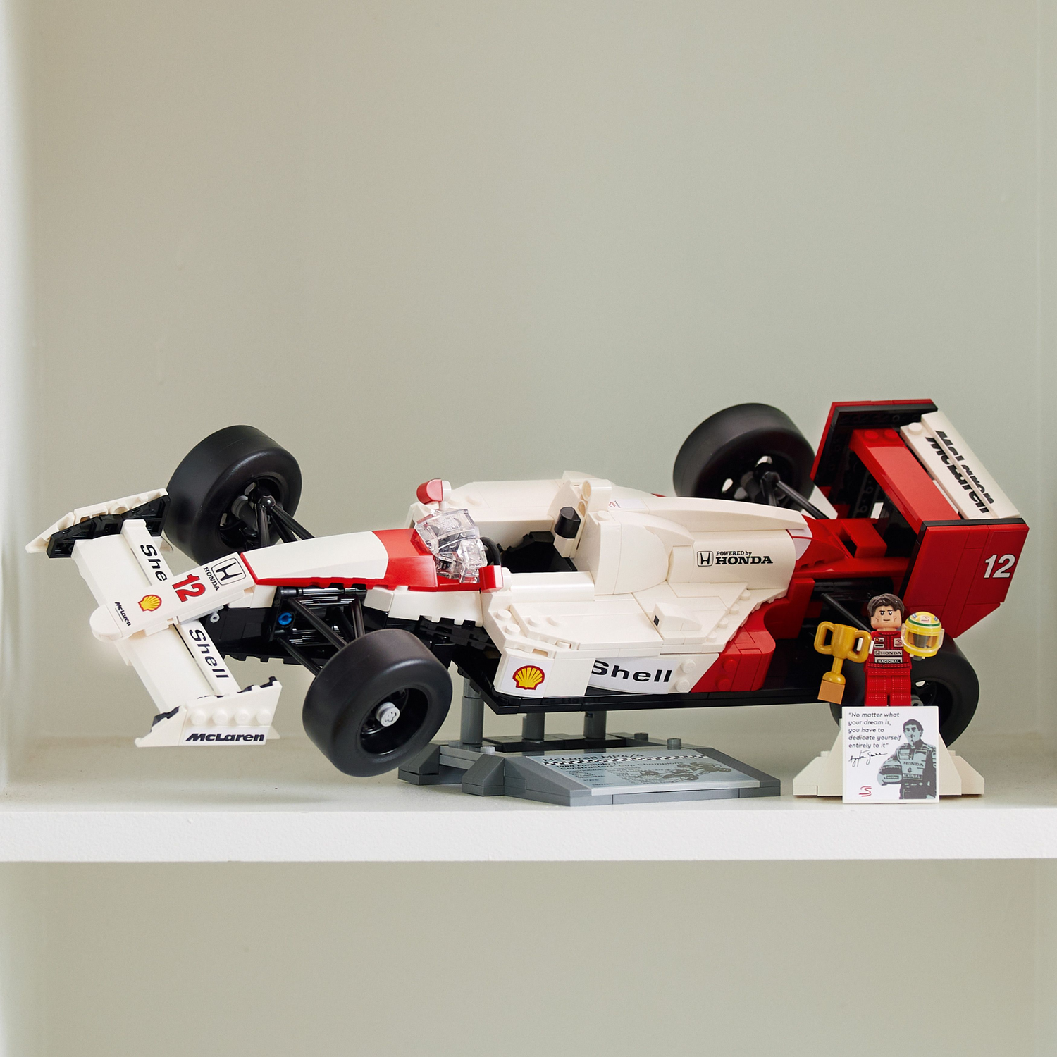 Lego McLaren raceauto op een plank. Witte en rode auto met een beeldje en een trofee.