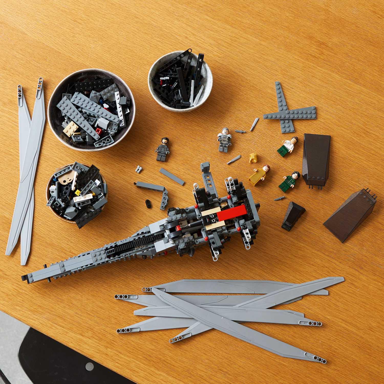Houten tafel met verspreide Lego-stukken, kommen en het Ornithopter-model in aanbouw.