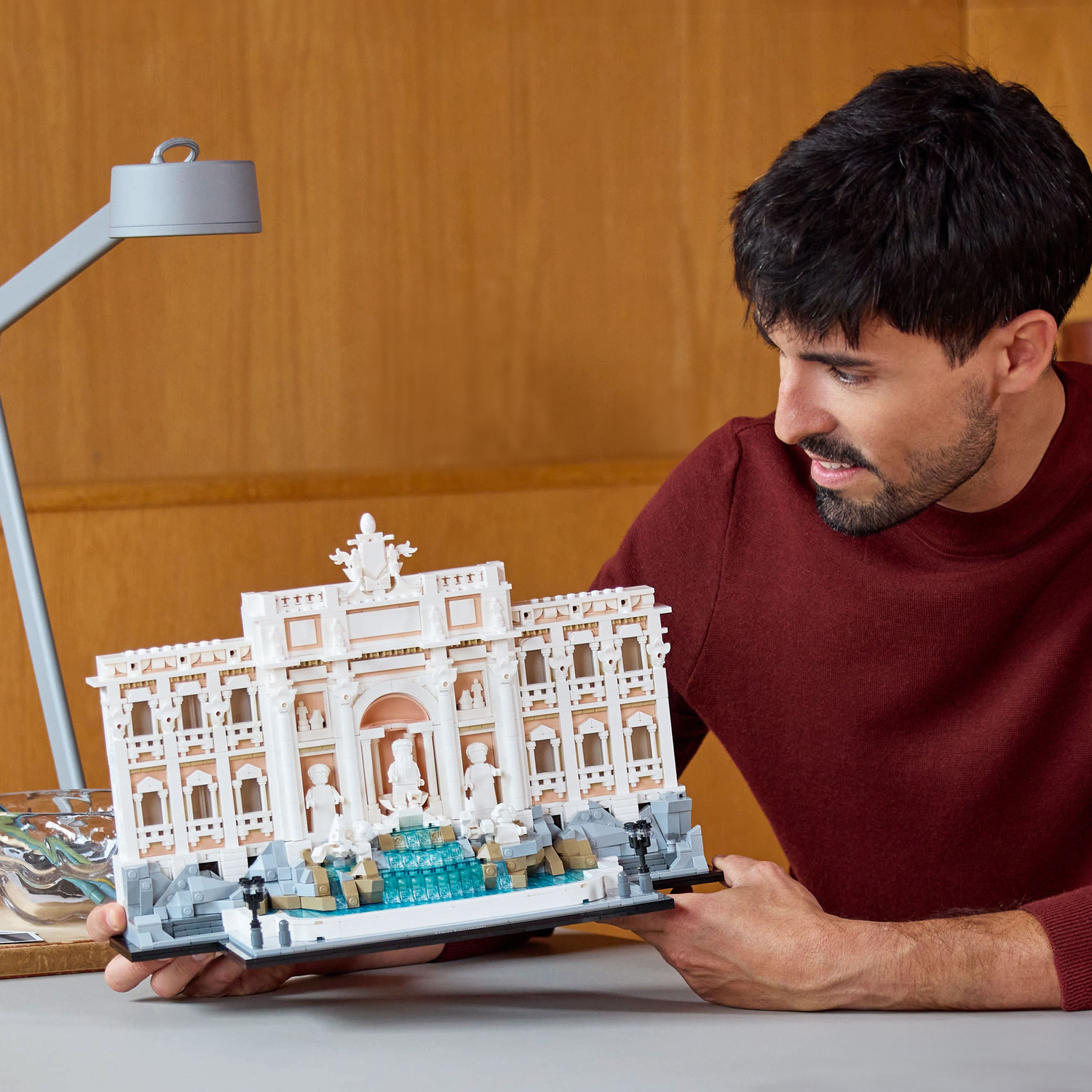 Man kijkt naar Lego Trevi Fontein model. Lamp, tafel en muur op de achtergrond.