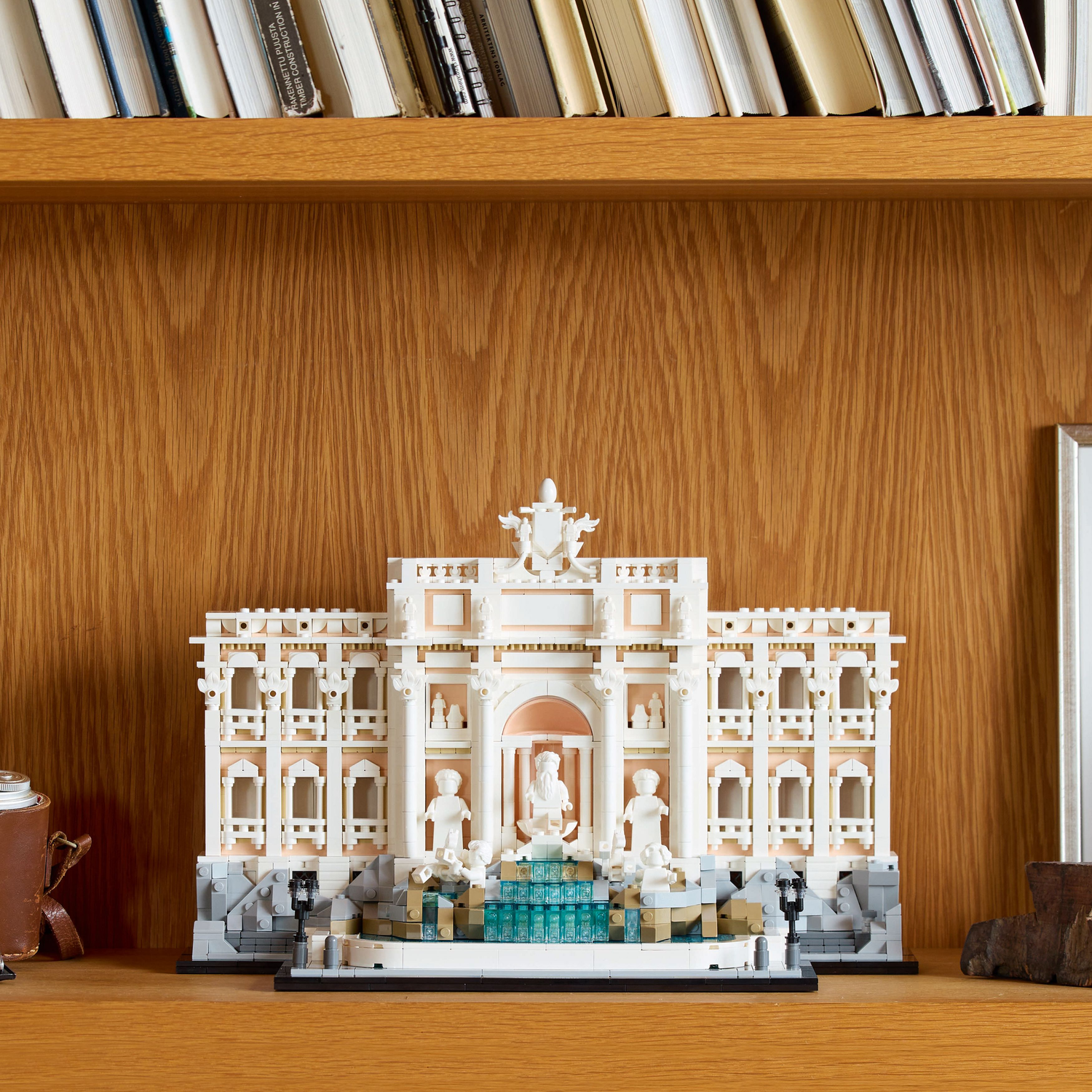 Lego Trevi Fontein model op een plank. Houten muur en boeken op de achtergrond.