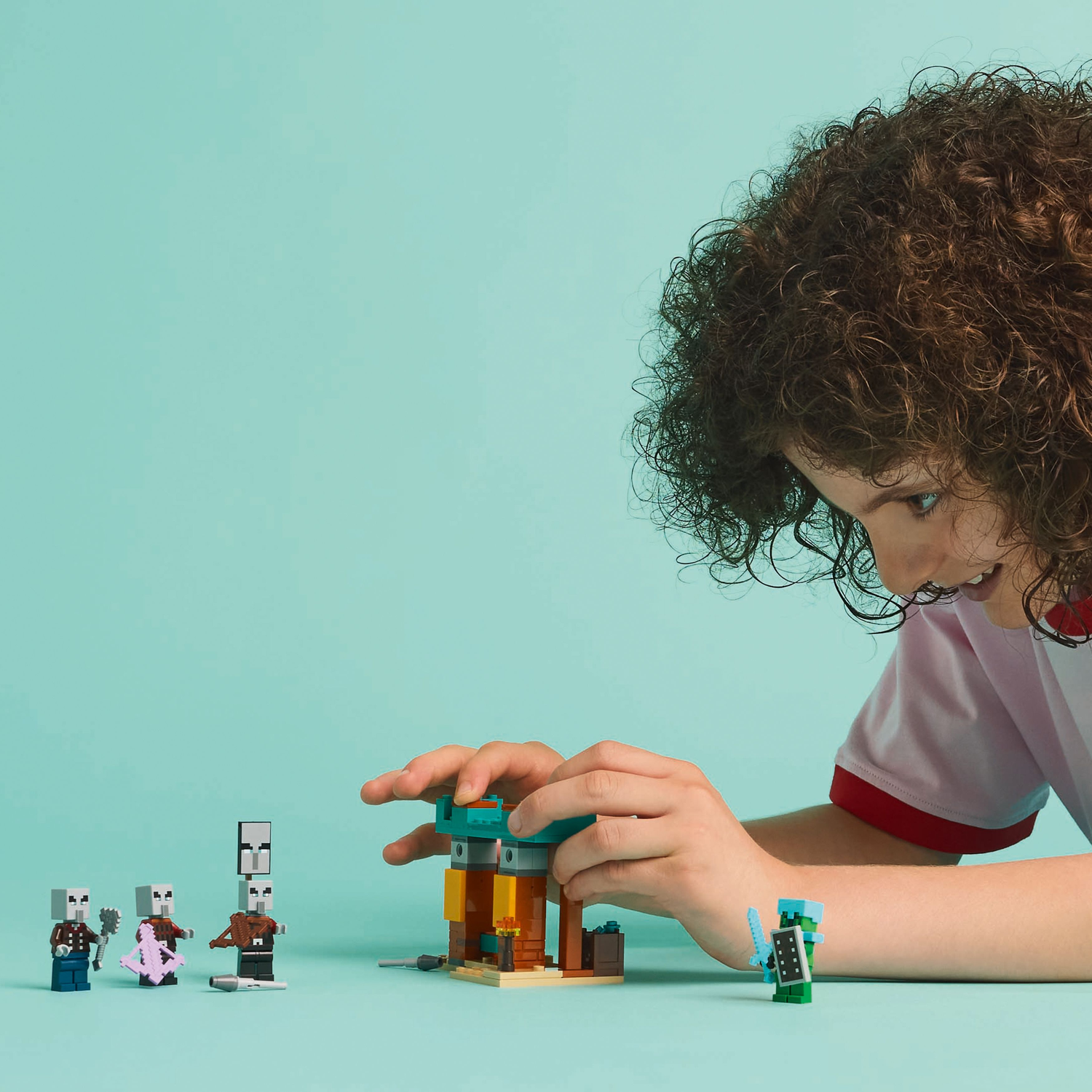 Een persoon speelt met Minecraft Lego sets, met personages en een structuur.
