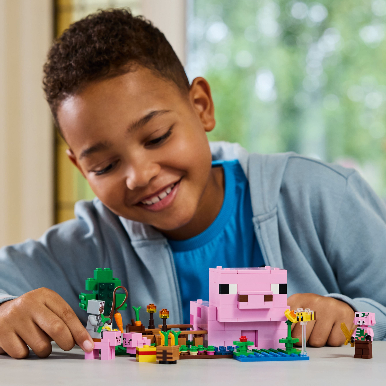 Een kind speelt vrolijk met een Lego Minecraft set met een roze varkenshuis.