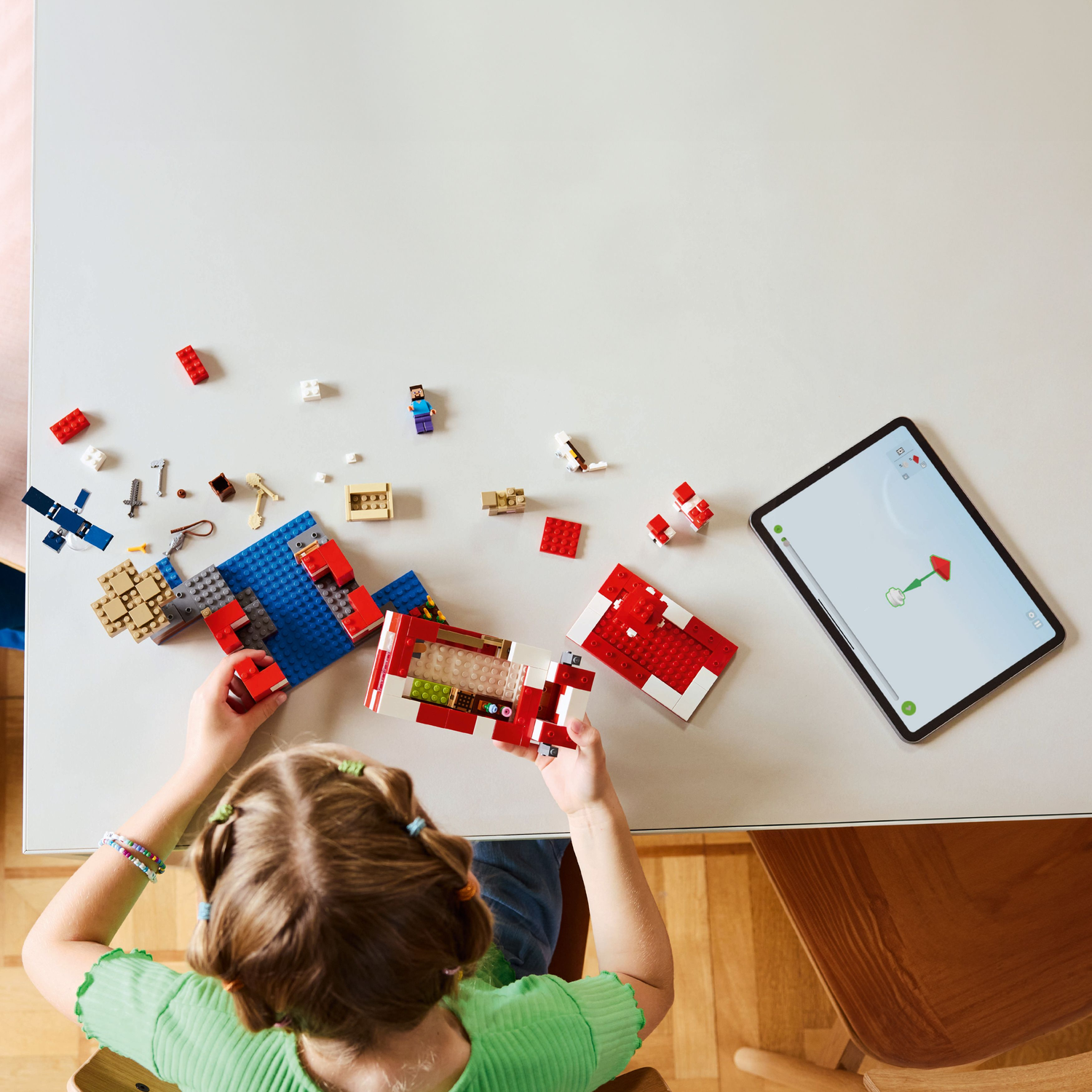 Hands assembling Minecraft Lego set, a red and white mushroom house.