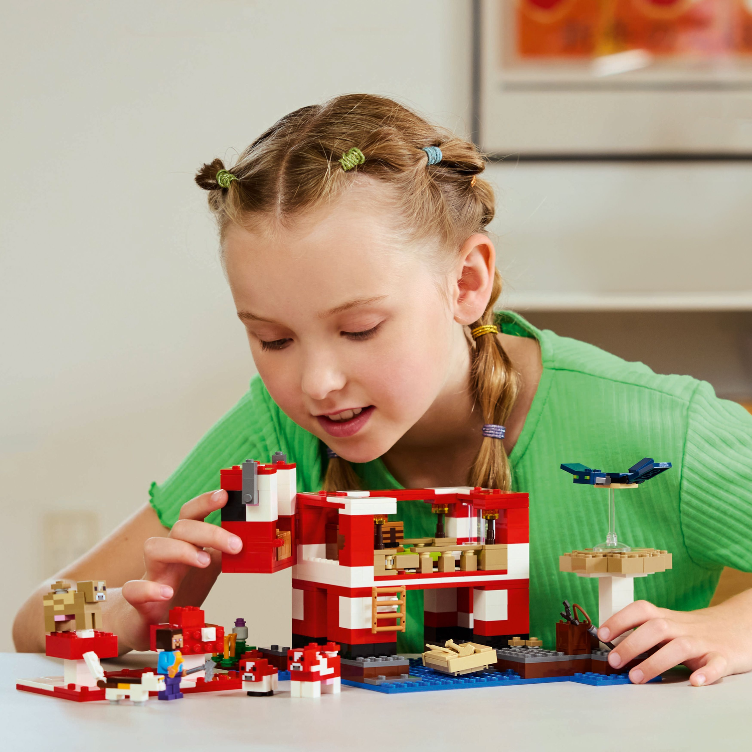 A child assembling a Minecraft Lego set: a red and white mushroom house.