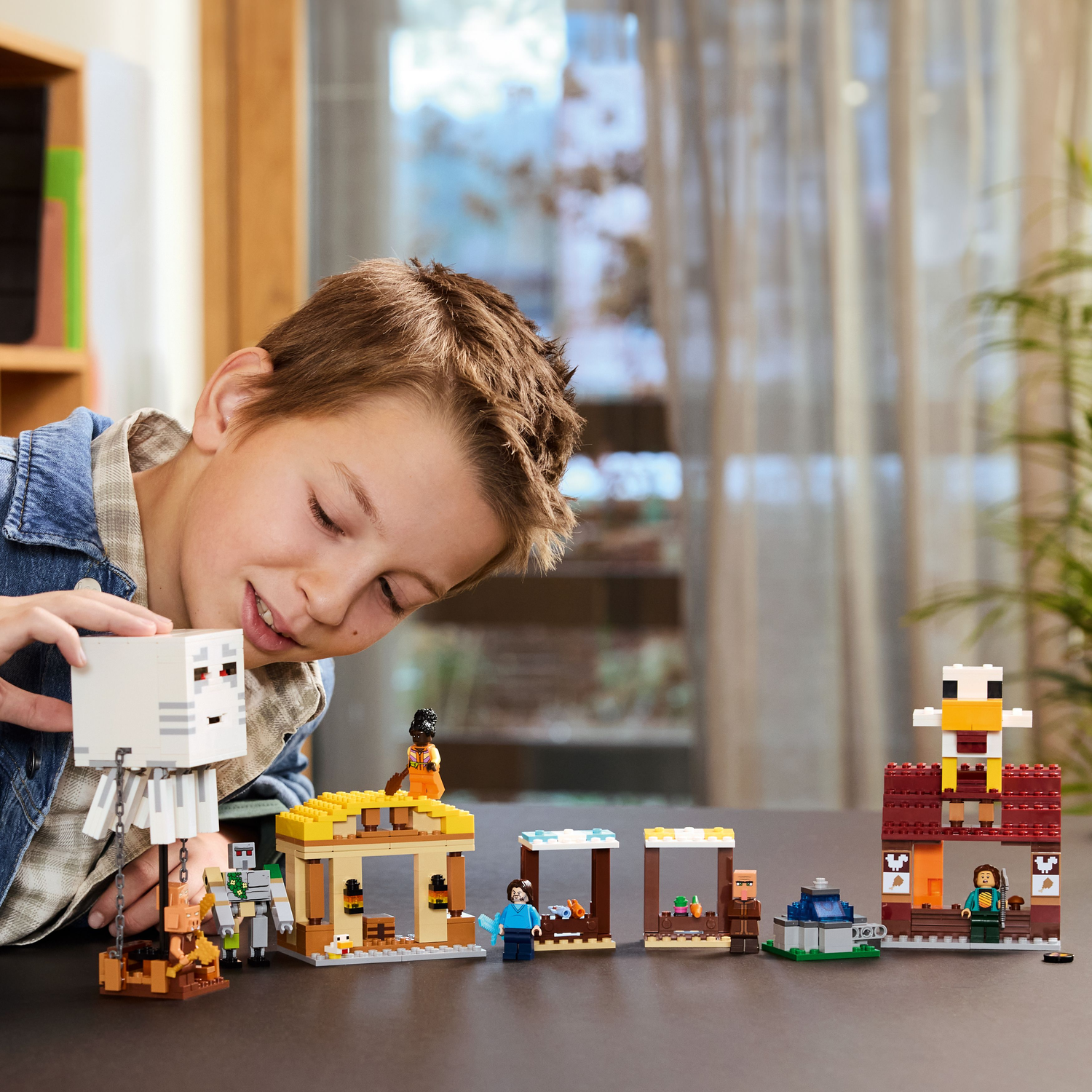 Een kind bekijkt een Lego Minecraft set, met verschillende figuren en structuren op de tafel. De set bevat een spook.