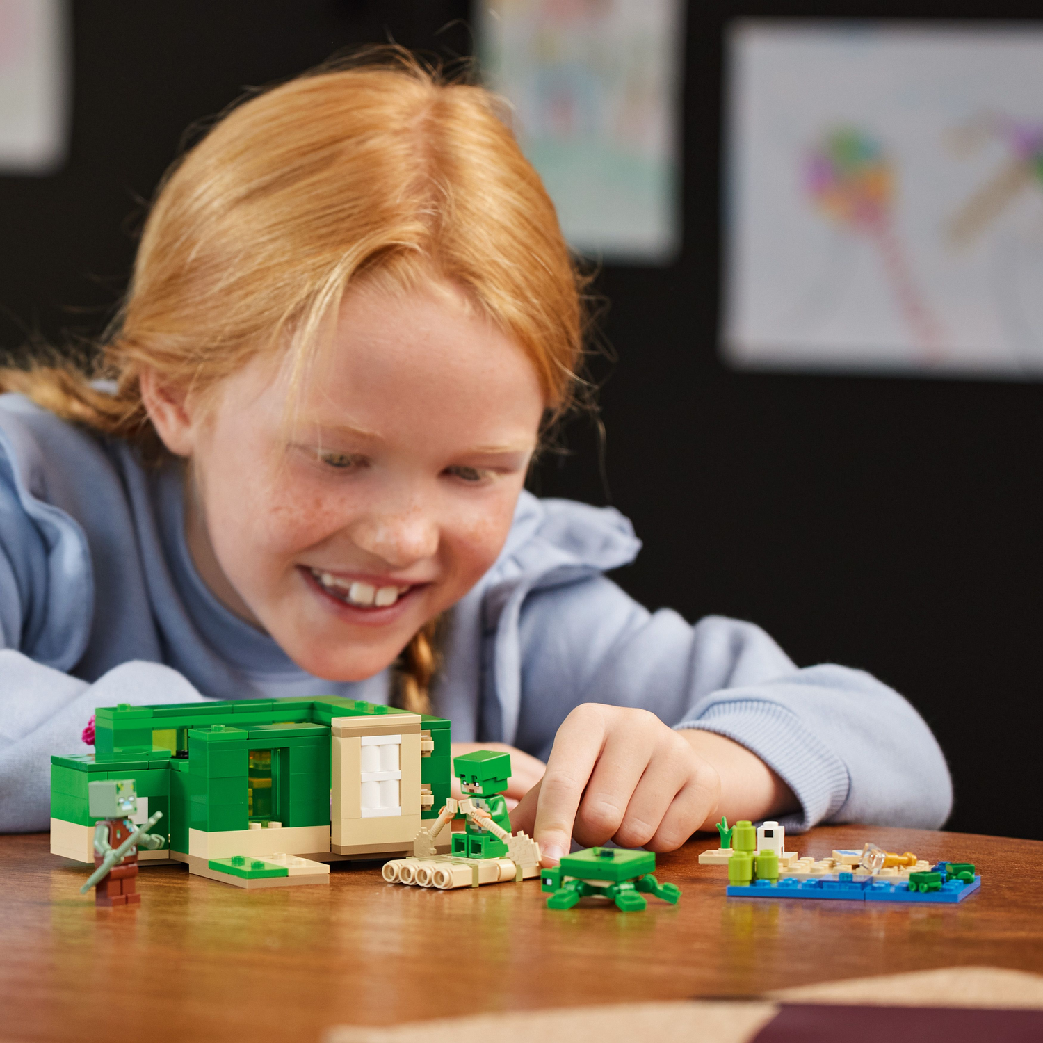 Een kind bekijkt een Lego Minecraft schildpaddenhuis set. De set bevat figuren, een huis en andere elementen.