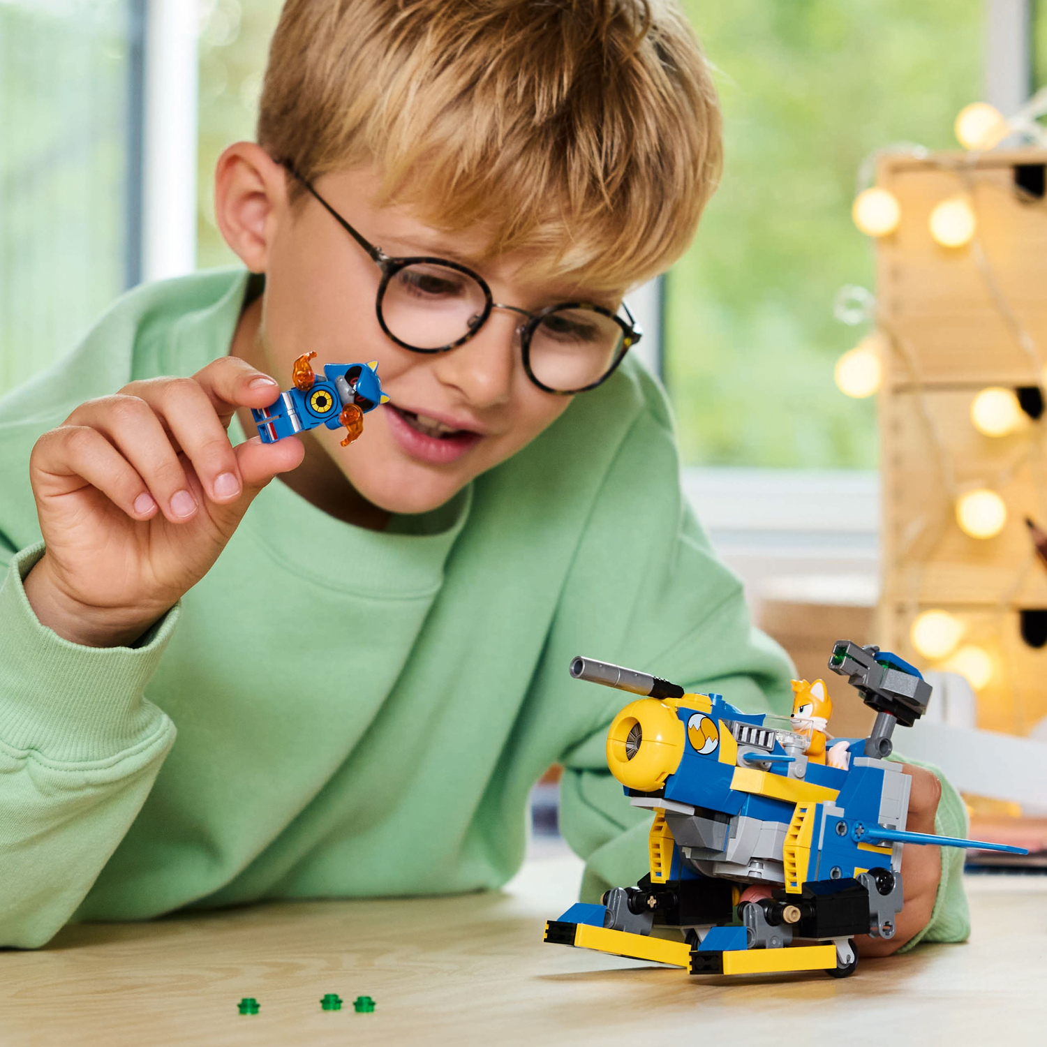 A boy plays with a Lego Sonic set with Tails, a mech, and Metal Sonic toy.