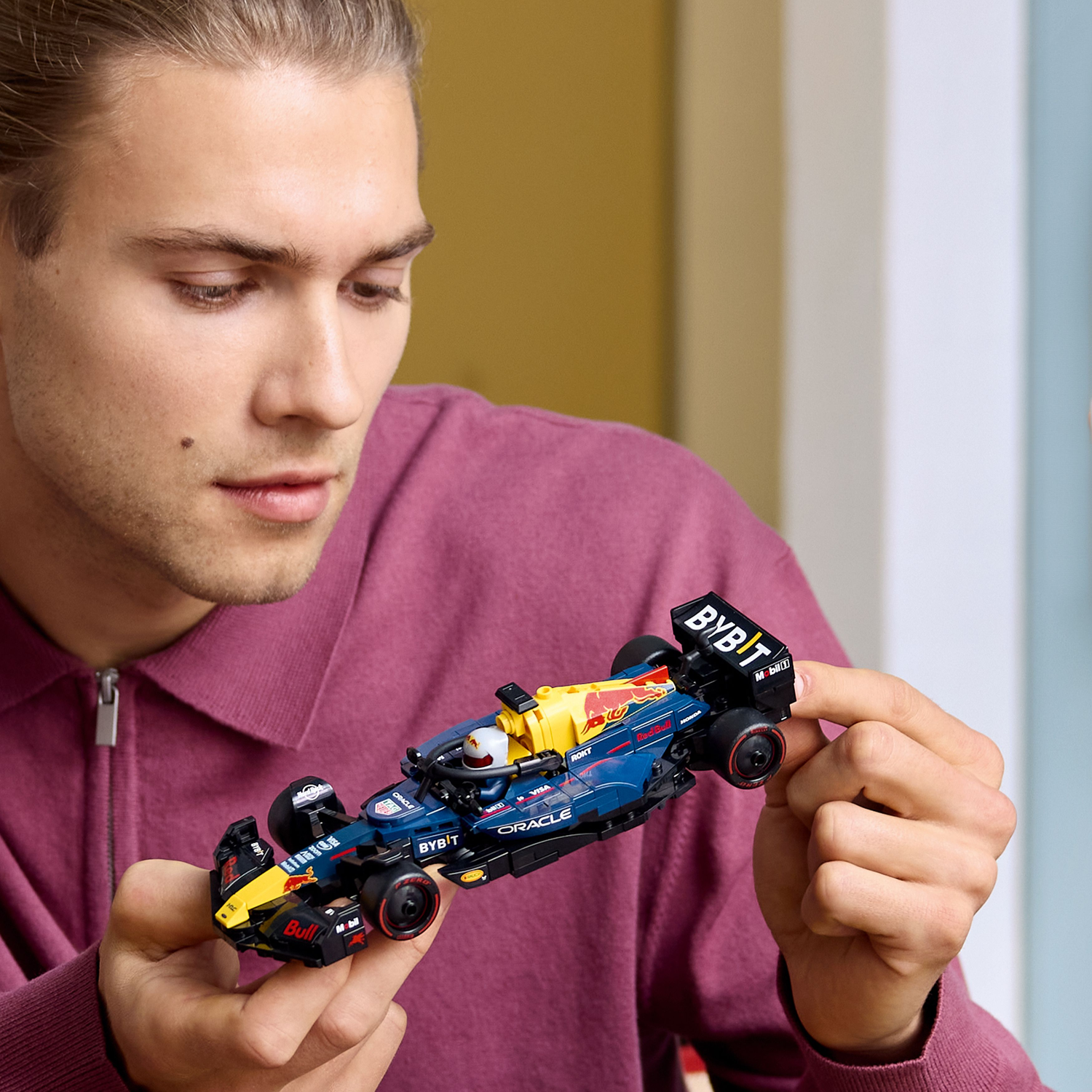 Man holding a blue and yellow LEGO Red Bull F1 car.