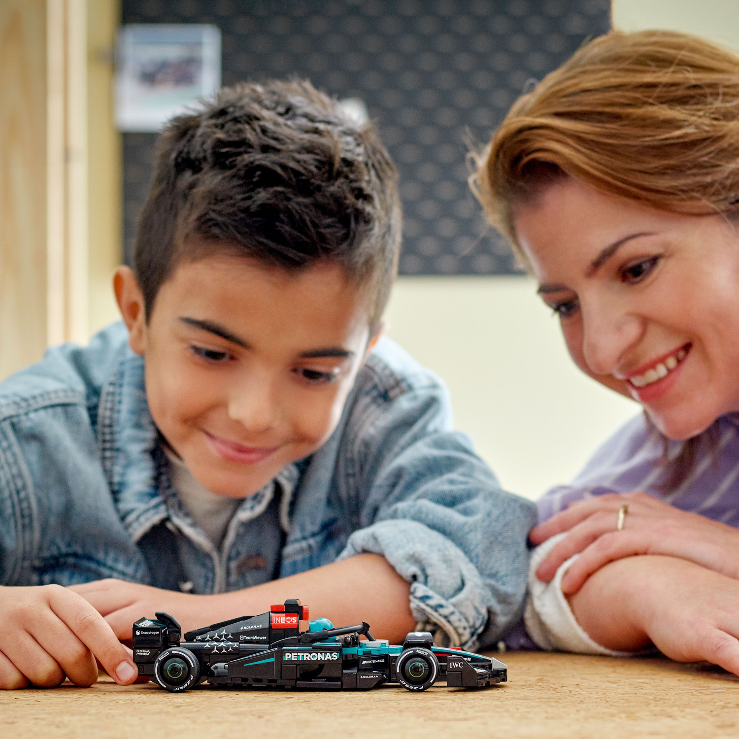 Green toy race car with a green figure next to it, both on black surface.