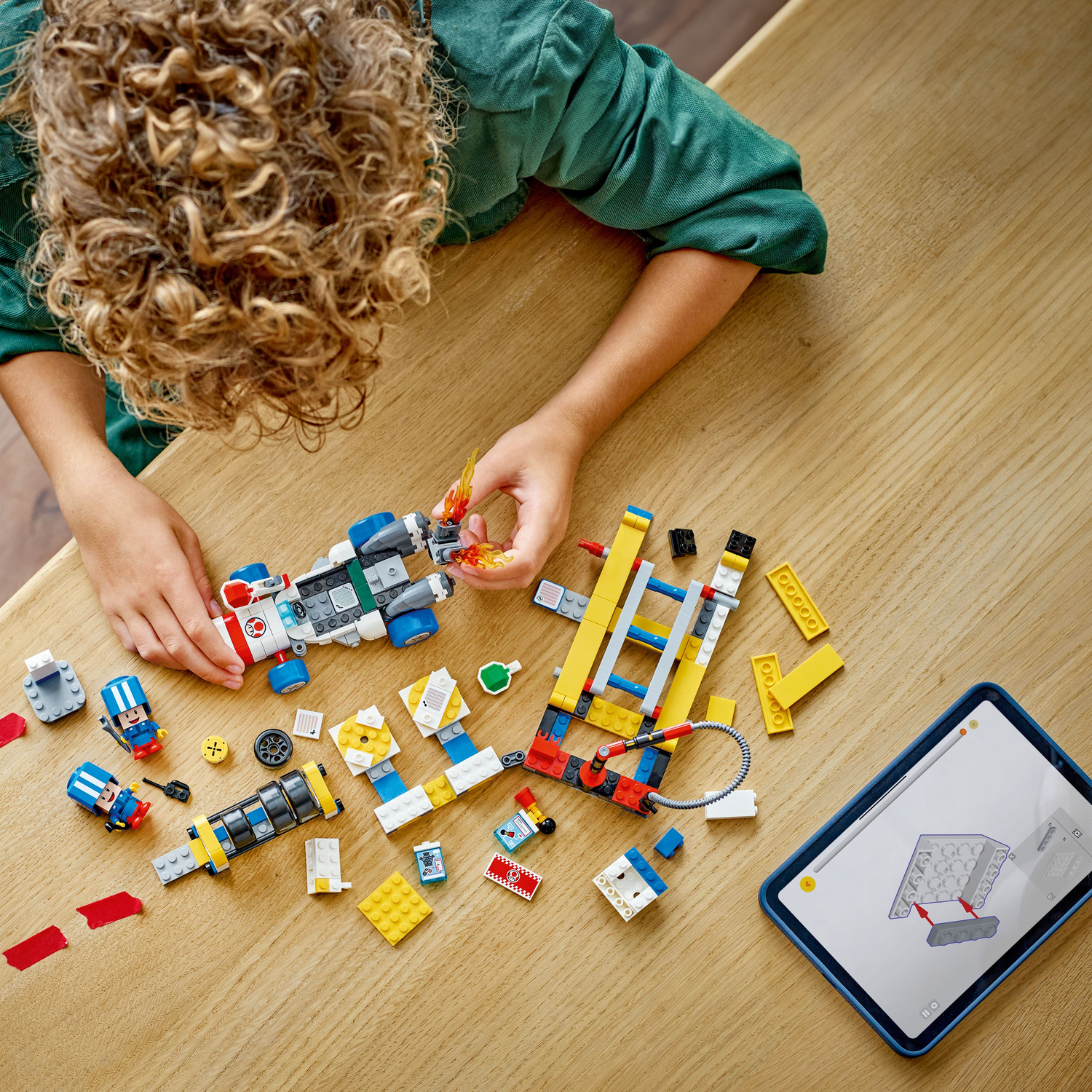 A child building a Lego Super Mario set. Lego pieces are scattered on a wooden table.