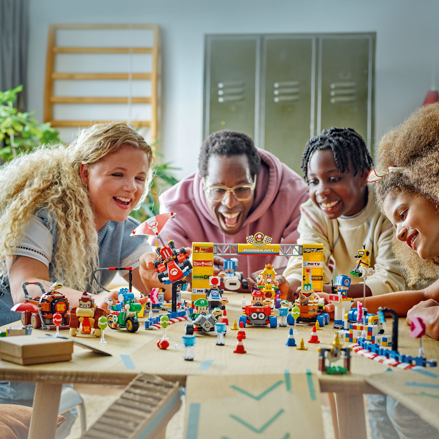 A group of people playing with a Lego Super Mario set, featuring a race track.